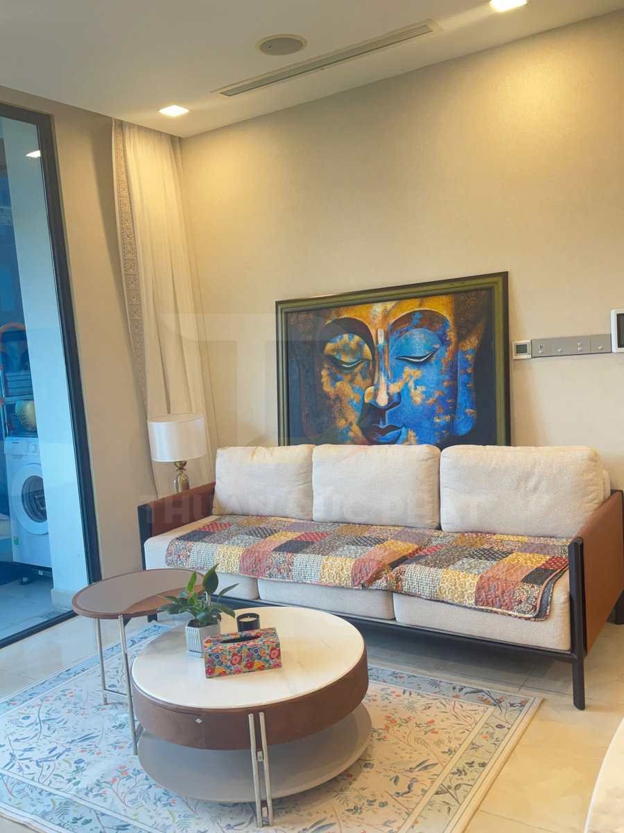 Sofa vải màu kem với chăn patchwork nhiều màu và bàn trà tròn hiện đại trong phòng khách sáng sủa