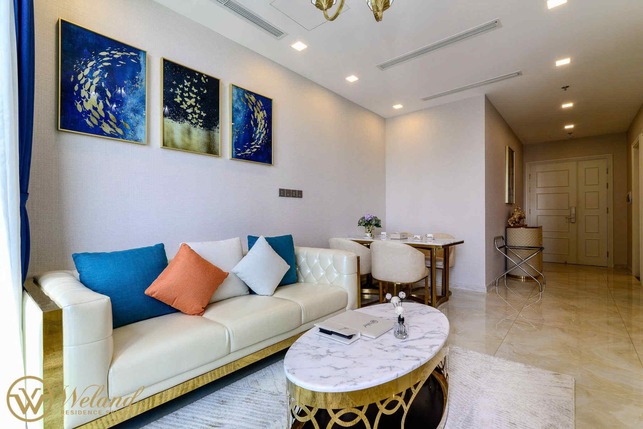 Phòng khách căn hộ cao cấp với sofa da kem, bàn trà mặt đá và tranh treo tường xanh vàng hiện đại