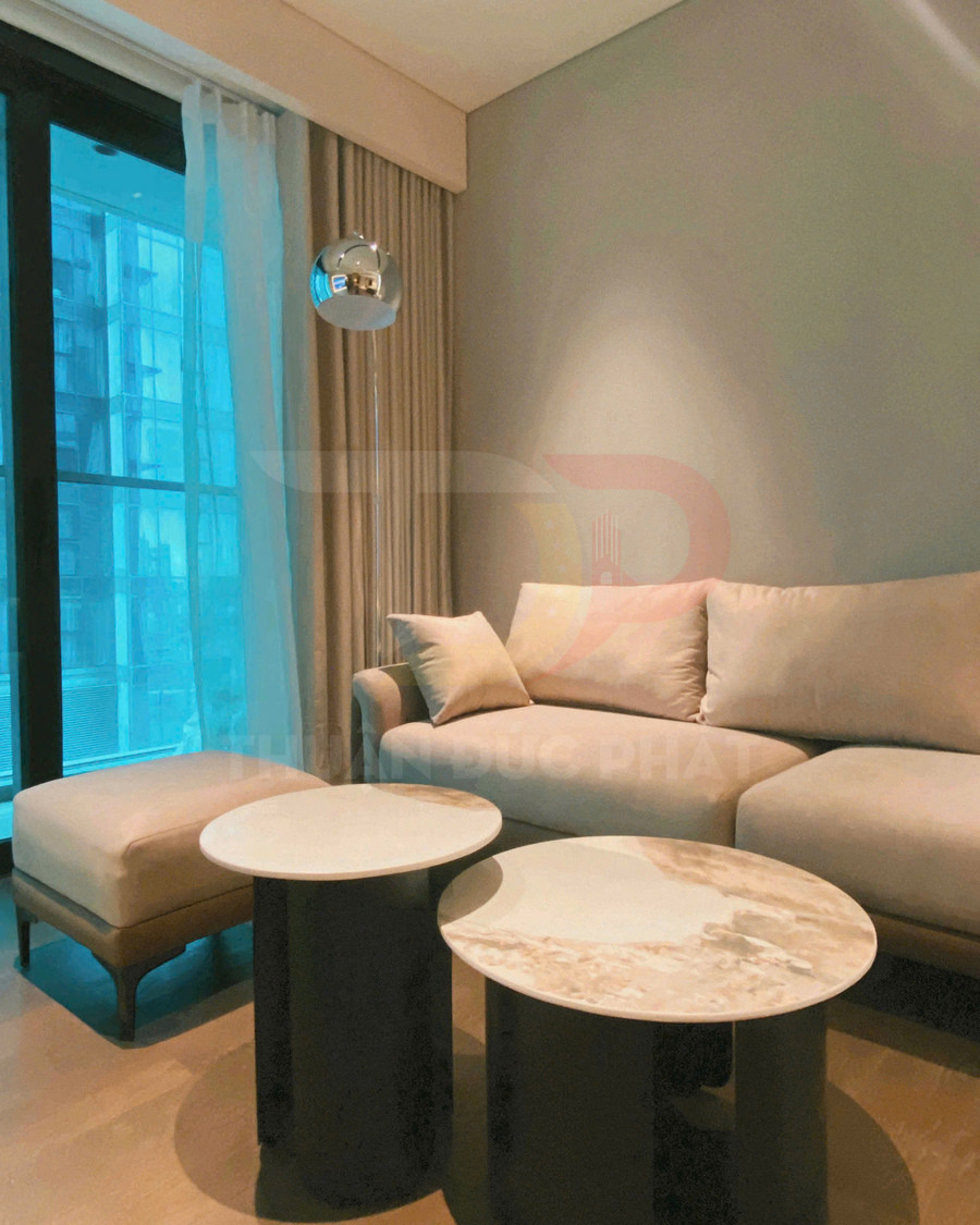 Bàn trà tròn mặt đá đôi màu trắng kem đặt trước sofa vải màu be trong phòng khách hiện đại