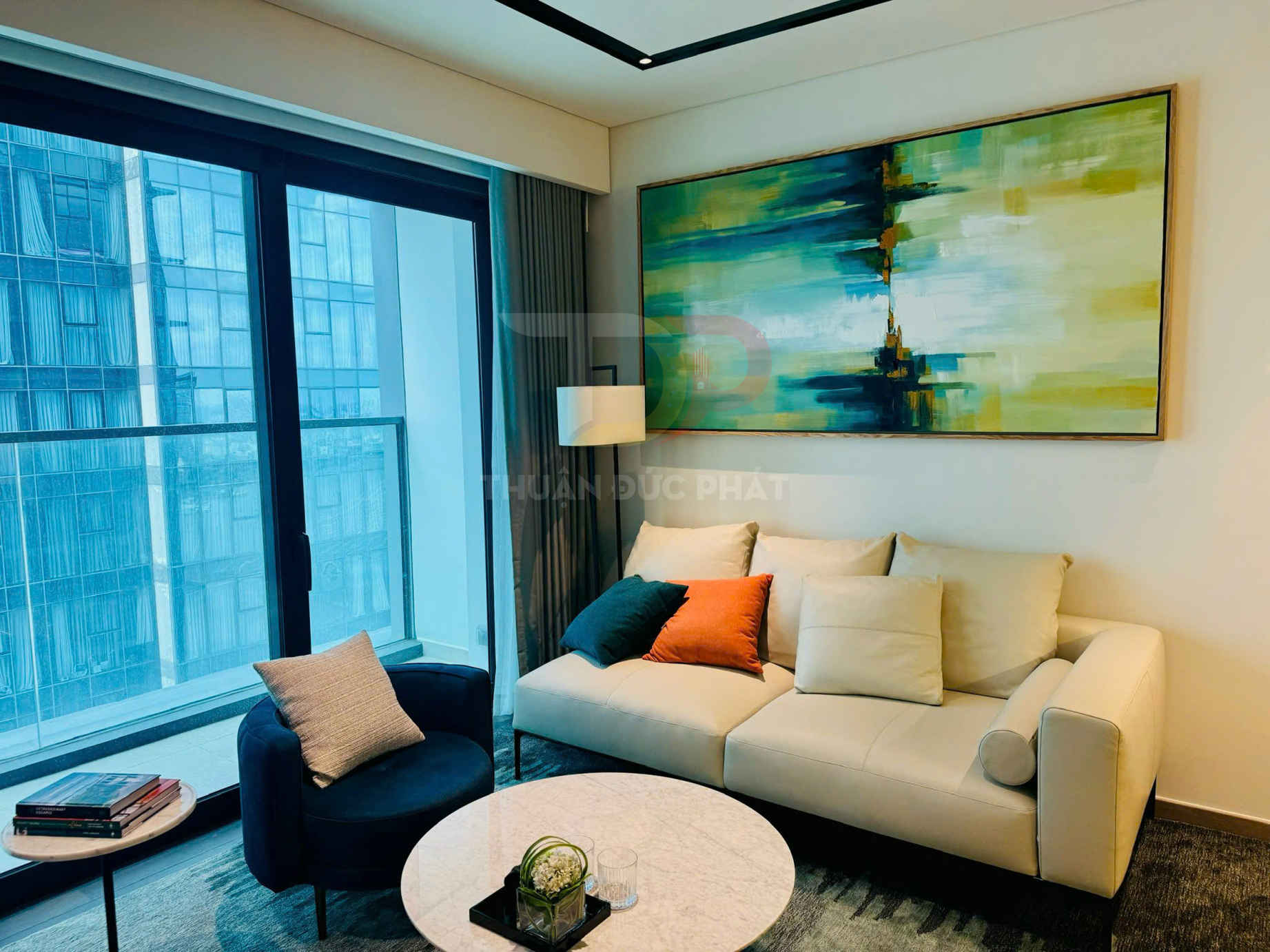 Phòng khách hiện đại với sofa da màu kem, bàn trà tròn đá marble và tranh treo tường trừu tượng lớn