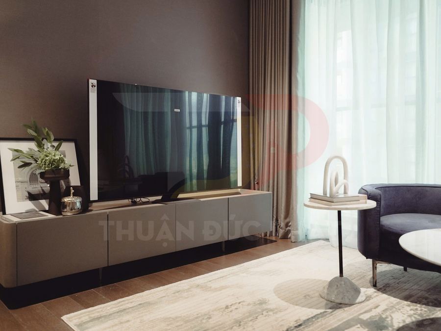 Tivi màn hình phẳng đặt trên kệ gỗ trong phòng khách hiện đại có sofa và bàn trà