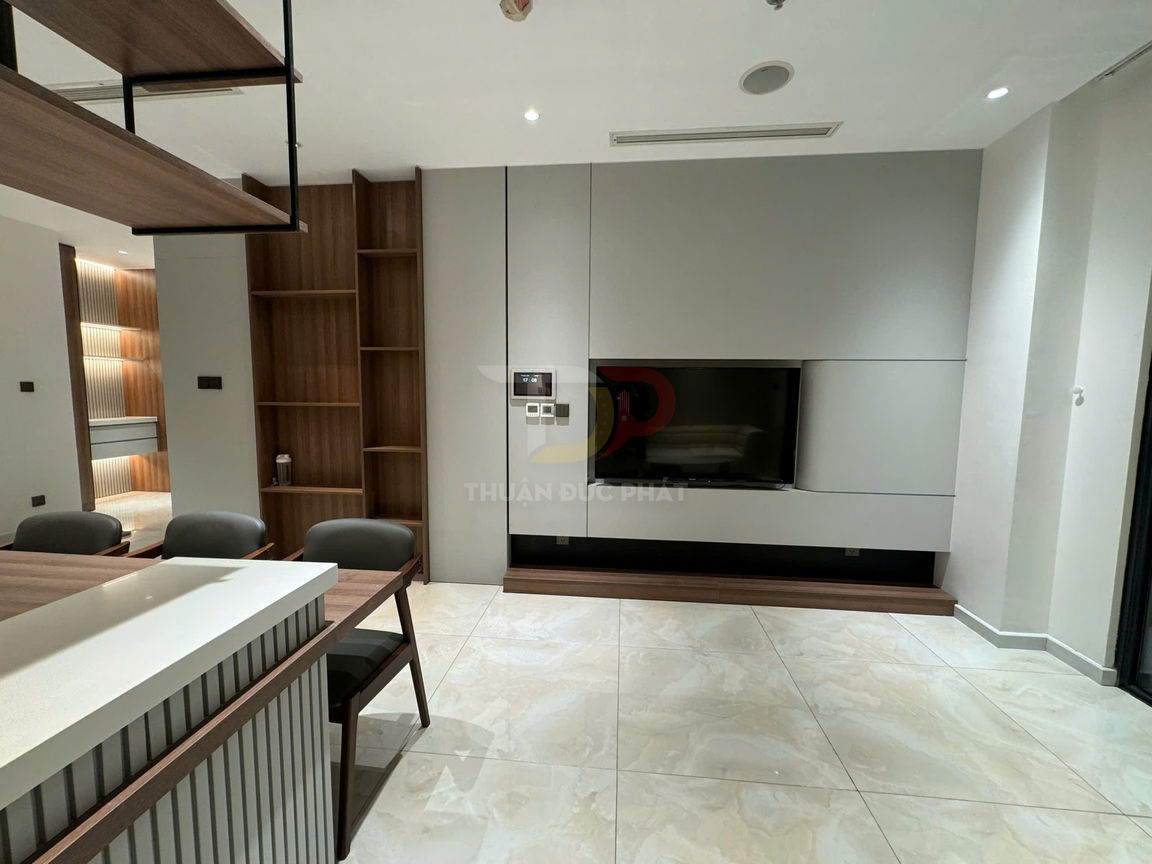 Phòng khách hiện đại với kệ tivi gỗ, tivi treo tường và bộ bàn ghế ăn cạnh bếp