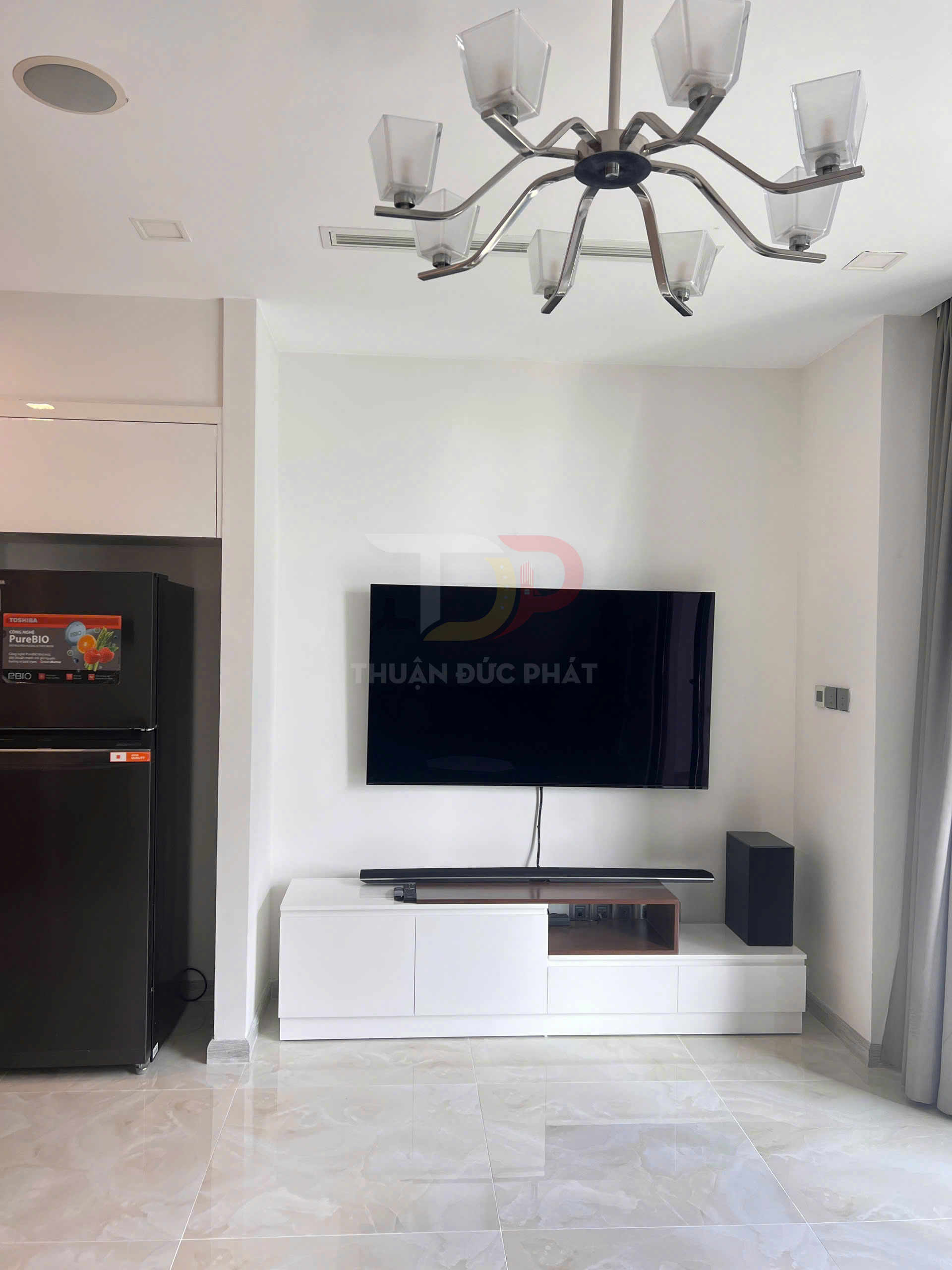 Kệ tivi phòng khách hiện đại với tivi treo tường, loa soundbar và tủ kệ trắng tối giản