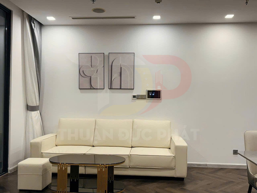 Sofa da màu kem với bàn trà mặt kính đen trong phòng khách hiện đại tường trắng