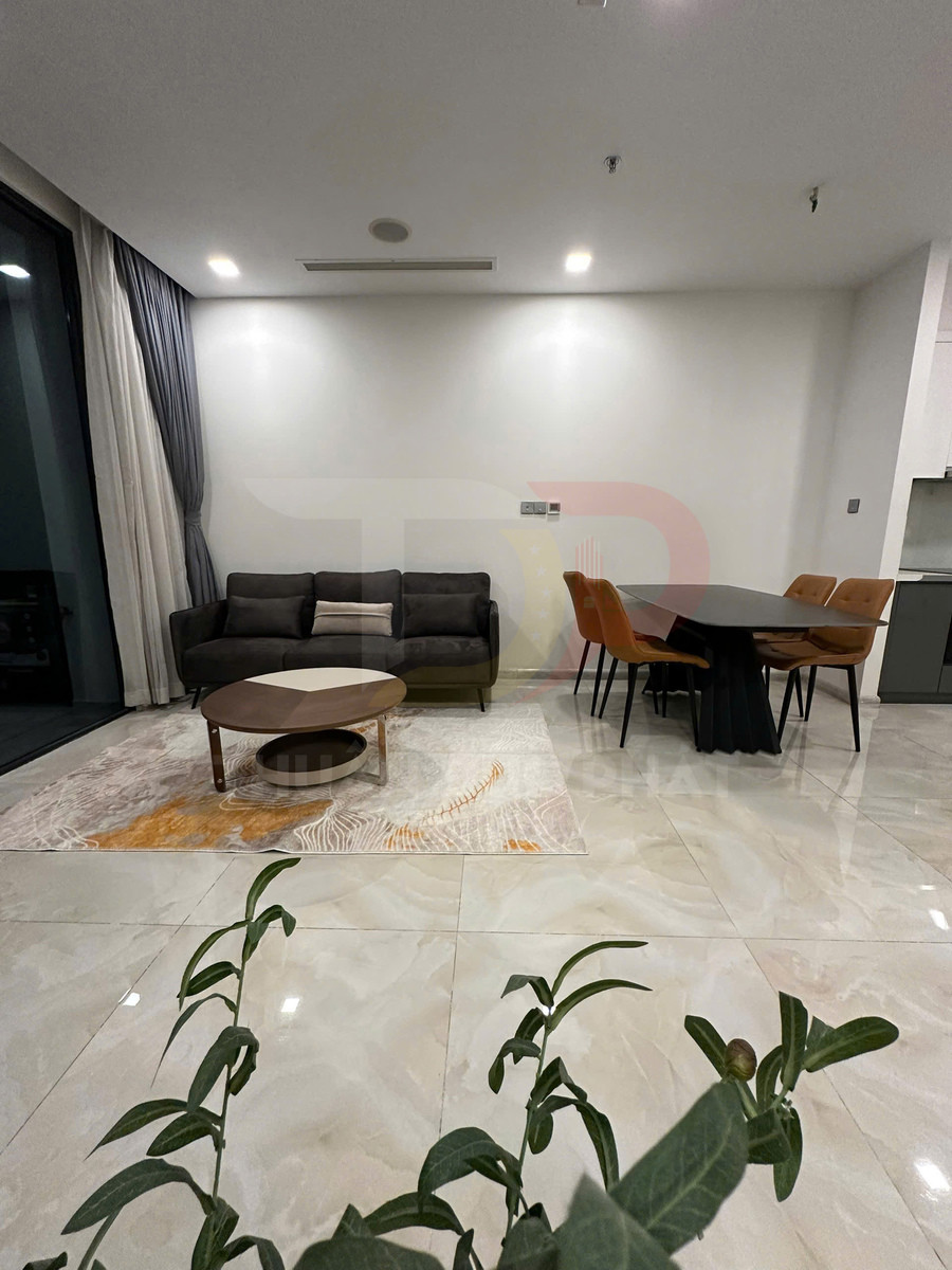 Phòng khách hiện đại với sofa nỉ tối màu, bàn trà gỗ tròn và bộ bàn ăn bốn ghế cạnh nhau