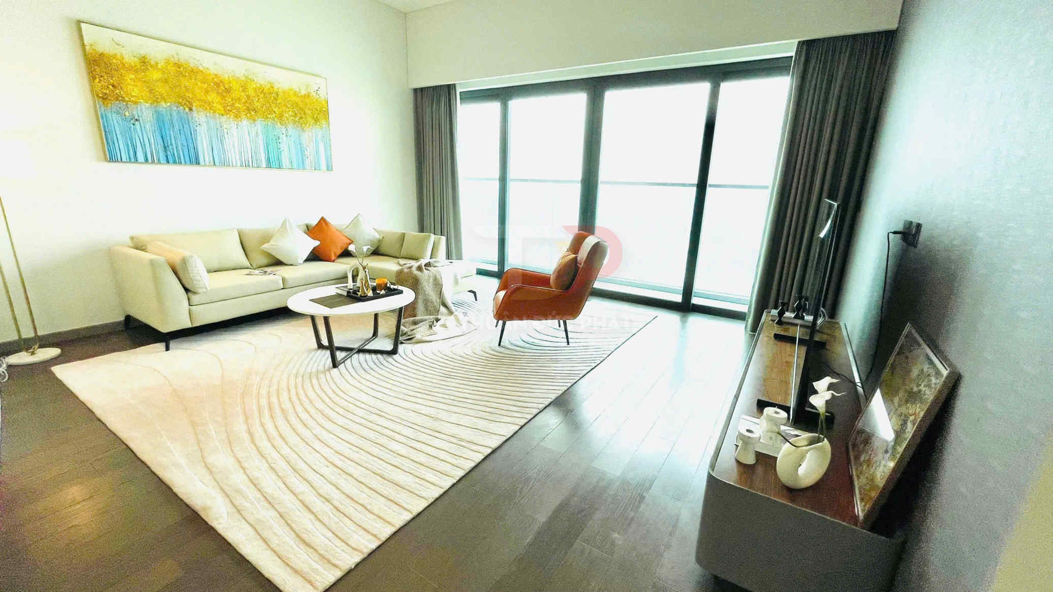 Phòng khách hiện đại với sofa kem, ghế bành cam, bàn trà gỗ và thảm lớn cạnh cửa kính ban công