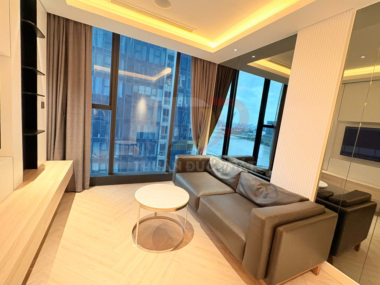 Sofa da màu nâu hiện đại trong phòng khách chung cư với cửa kính lớn nhìn ra thành phố