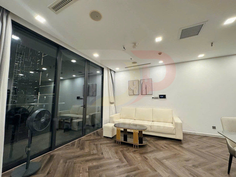 Sofa da màu kem với bàn trà kính chân kim loại trong phòng khách hiện đại sàn gỗ và cửa kính lớn