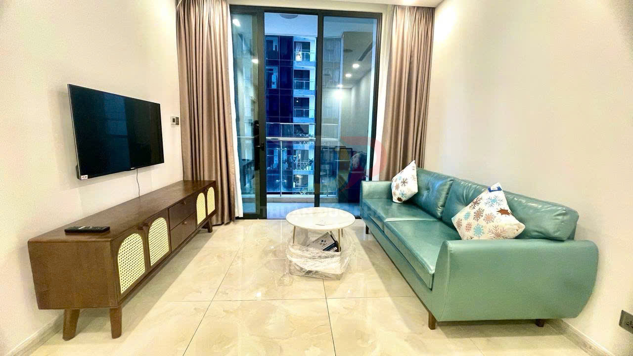 Sofa da màu xanh với bàn trà tròn và kệ tivi gỗ trong phòng khách chung cư hiện đại