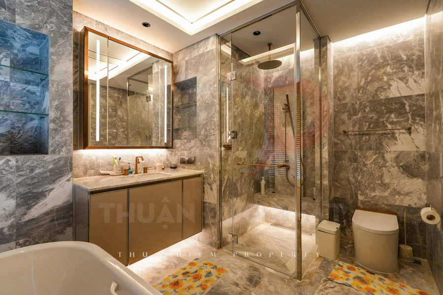 Phòng tắm cao cấp với buồng tắm kính, bồn cầu hiện đại và lavabo đá cẩm thạch sáng