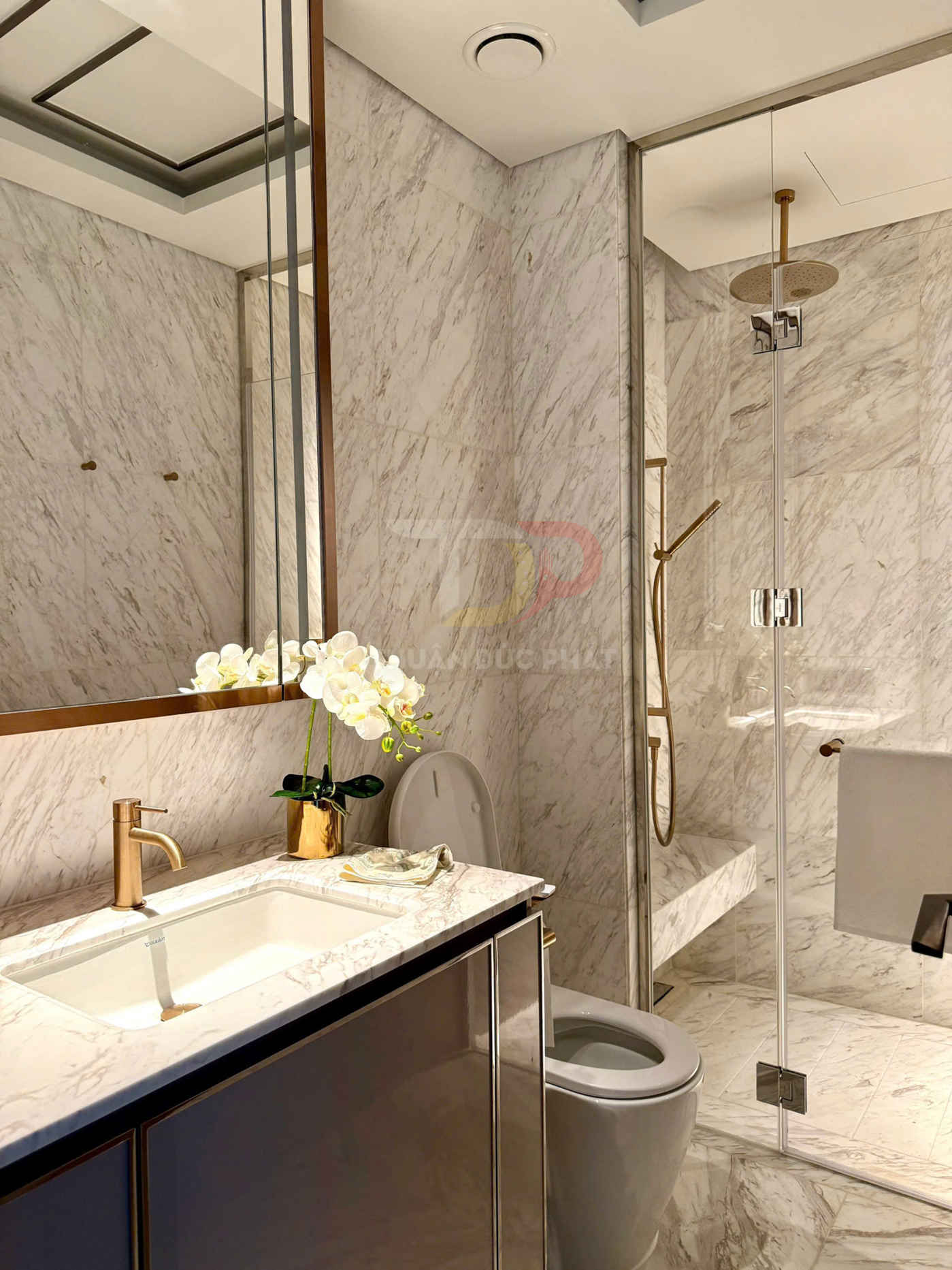 Phòng tắm đá cẩm thạch cao cấp với lavabo, vòi nước mạ vàng, bồn cầu và buồng tắm kính hiện đại