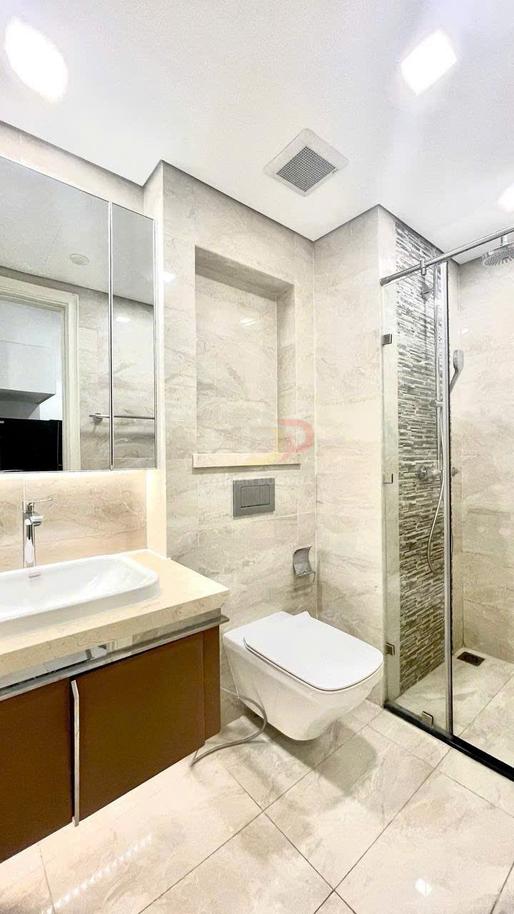 Phòng tắm hiện đại với bồn rửa mặt, bồn cầu treo tường và buồng tắm kính vách đá tự nhiên