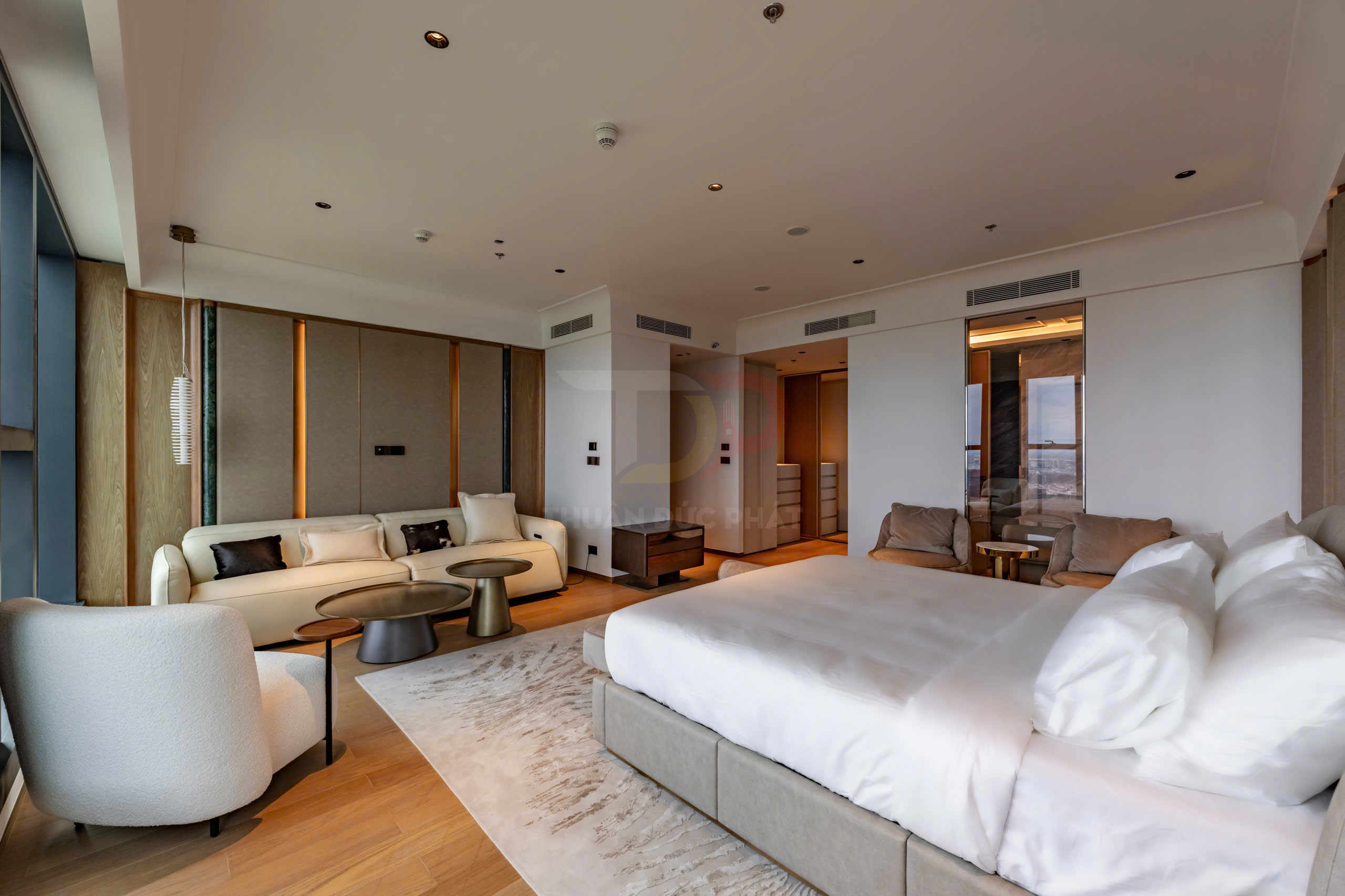 Phòng ngủ khách sạn cao cấp với giường lớn, sofa và bàn trà hiện đại, sàn gỗ sáng màu