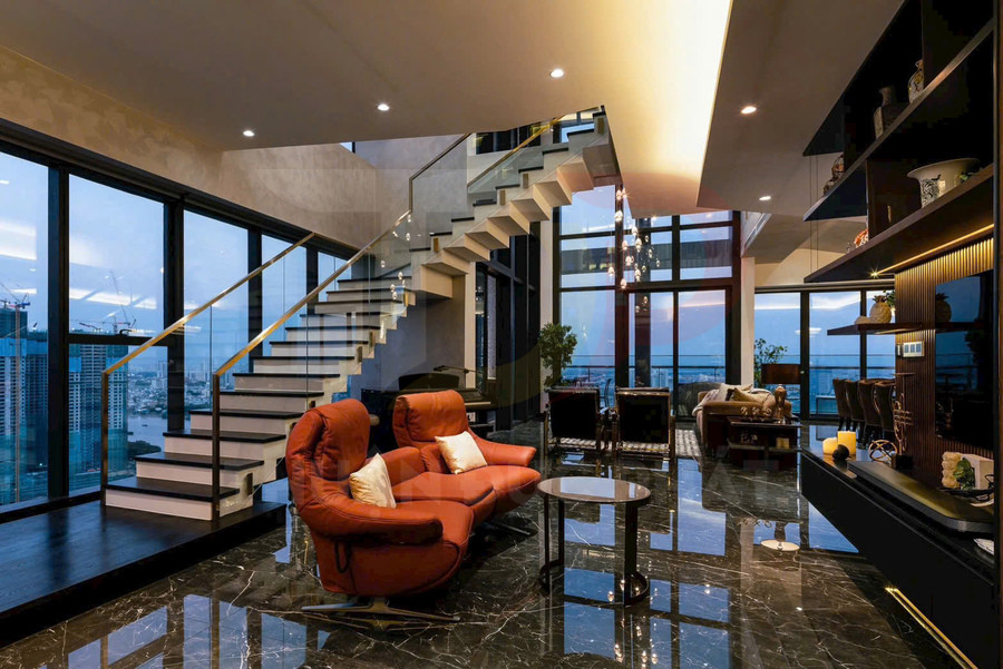 Phòng khách penthouse sang trọng với ghế sofa da màu cam, cầu thang kính và sàn đá hoa cương bóng