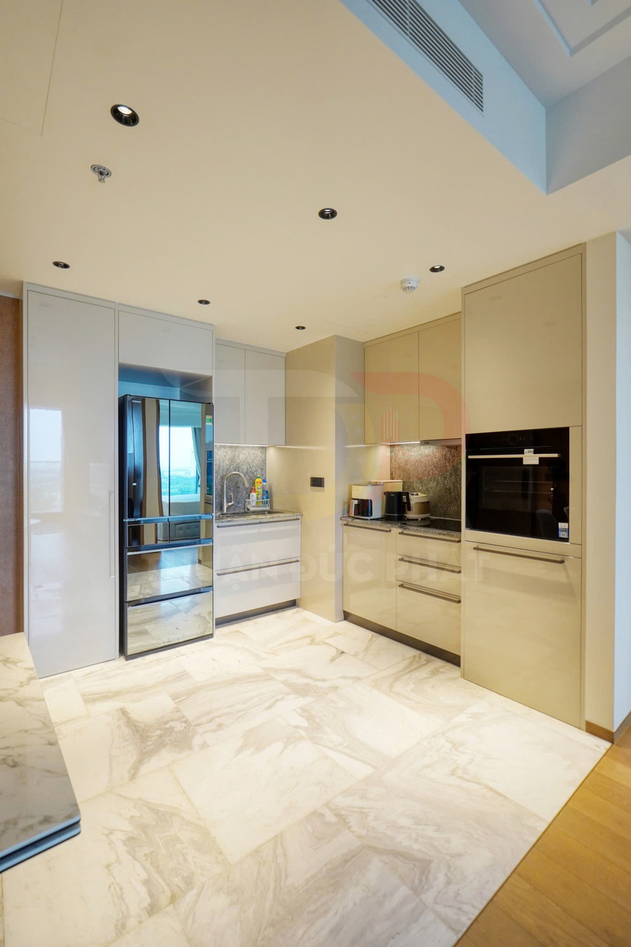 Bếp hiện đại với tủ bếp âm tường, tủ lạnh inox, lò nướng âm và mặt bếp đá sáng