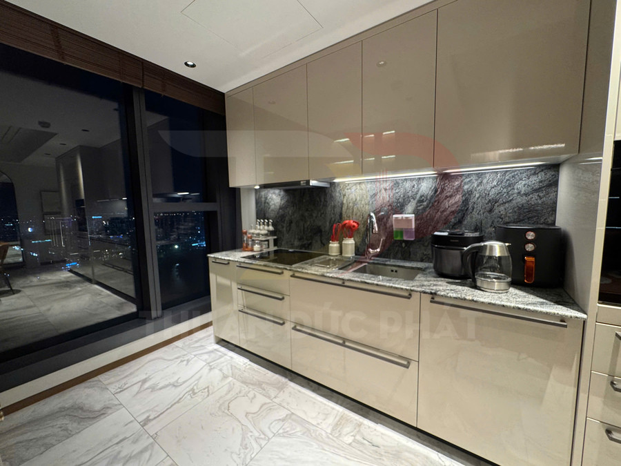 Tủ bếp hiện đại mặt đá granite với bếp từ, nồi chiên không dầu, nồi cơm điện và ấm siêu tốc trong căn hộ cao cấp