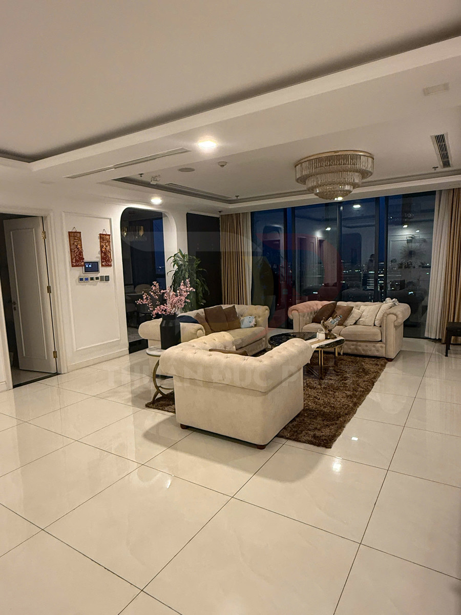 Phòng khách sang trọng với bộ sofa nỉ màu kem, bàn trà kính và đèn chùm trần hiện đại