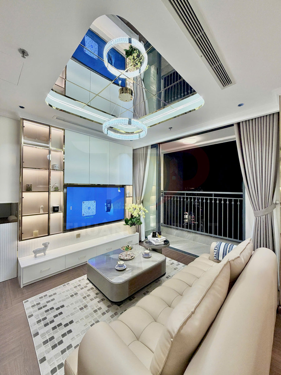 Phòng khách hiện đại với sofa da màu be, bàn trà chữ nhật và kệ tivi treo tường cạnh cửa kính ban công