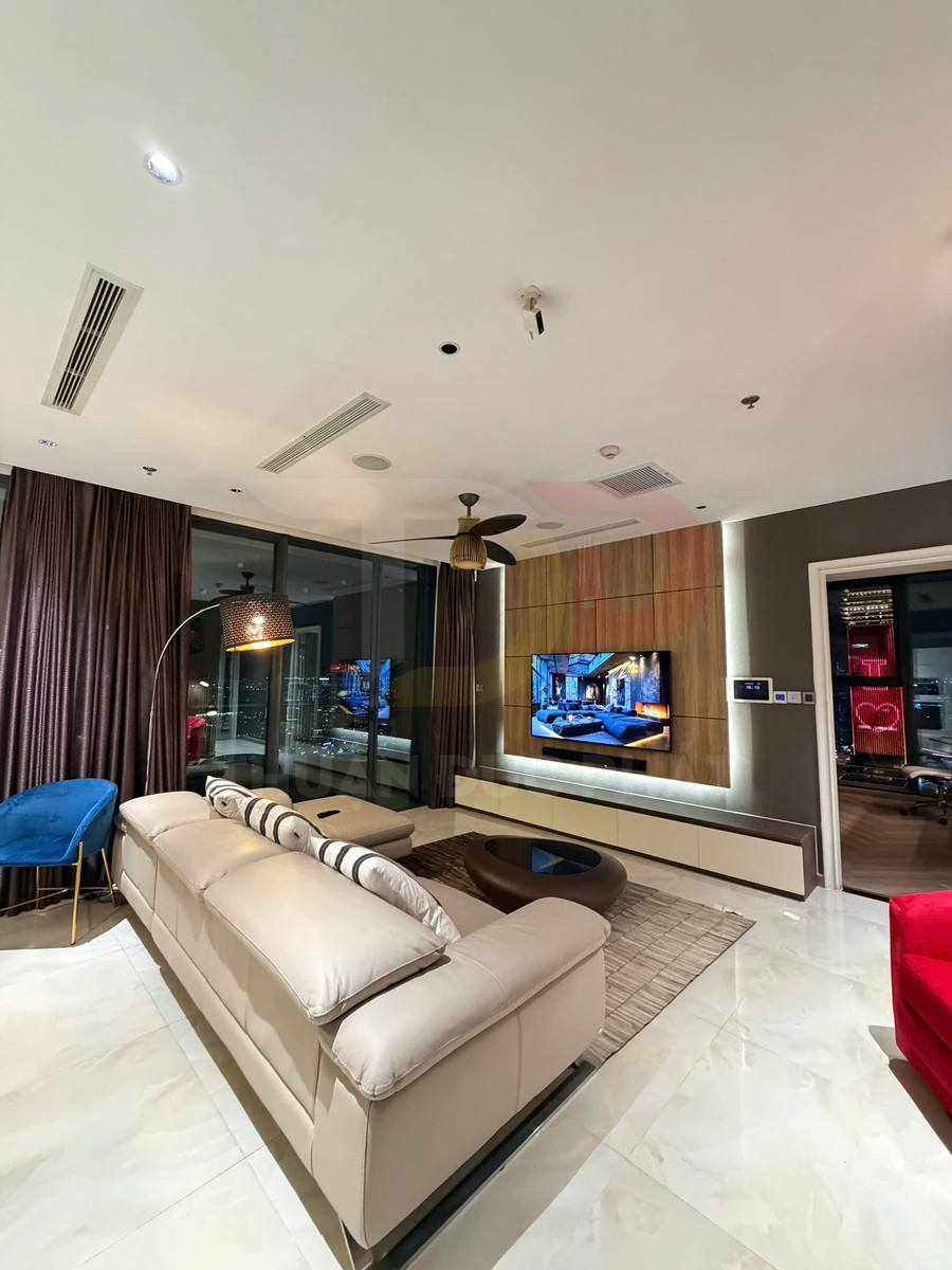 Phòng khách hiện đại với sofa da màu kem, bàn trà gỗ và tivi treo tường cạnh cửa kính lớn