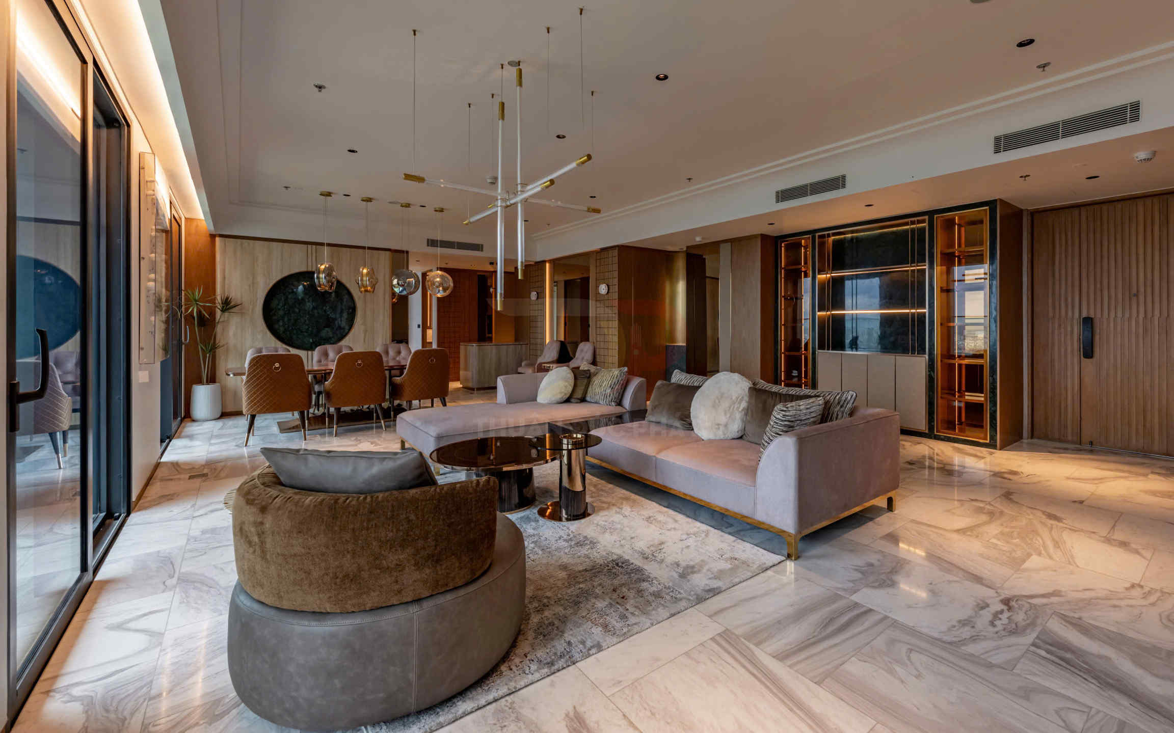 Phòng khách cao cấp với sofa bọc nỉ, bàn trà tròn mặt kính và bộ bàn ăn sang trọng trên nền gạch đá marble