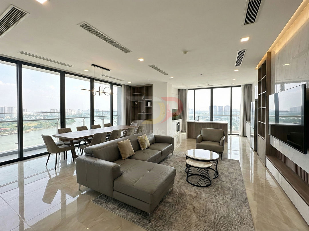 Phòng khách căn hộ cao cấp với sofa da xám, bàn trà tròn và bàn ăn lớn cạnh cửa kính toàn cảnh sông