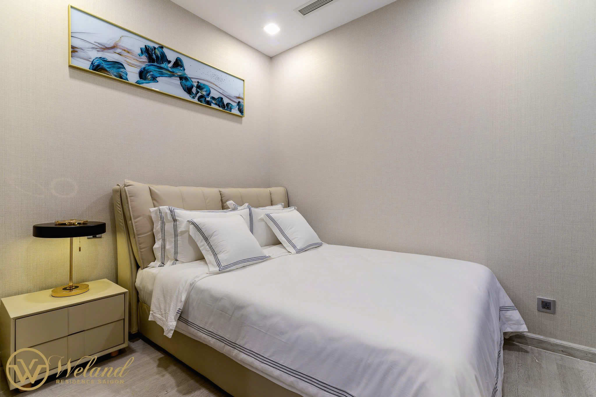 Bộ chăn ga gối màu trắng đơn giản trên giường ngủ hiện đại cạnh bàn đầu giường và đèn trang trí