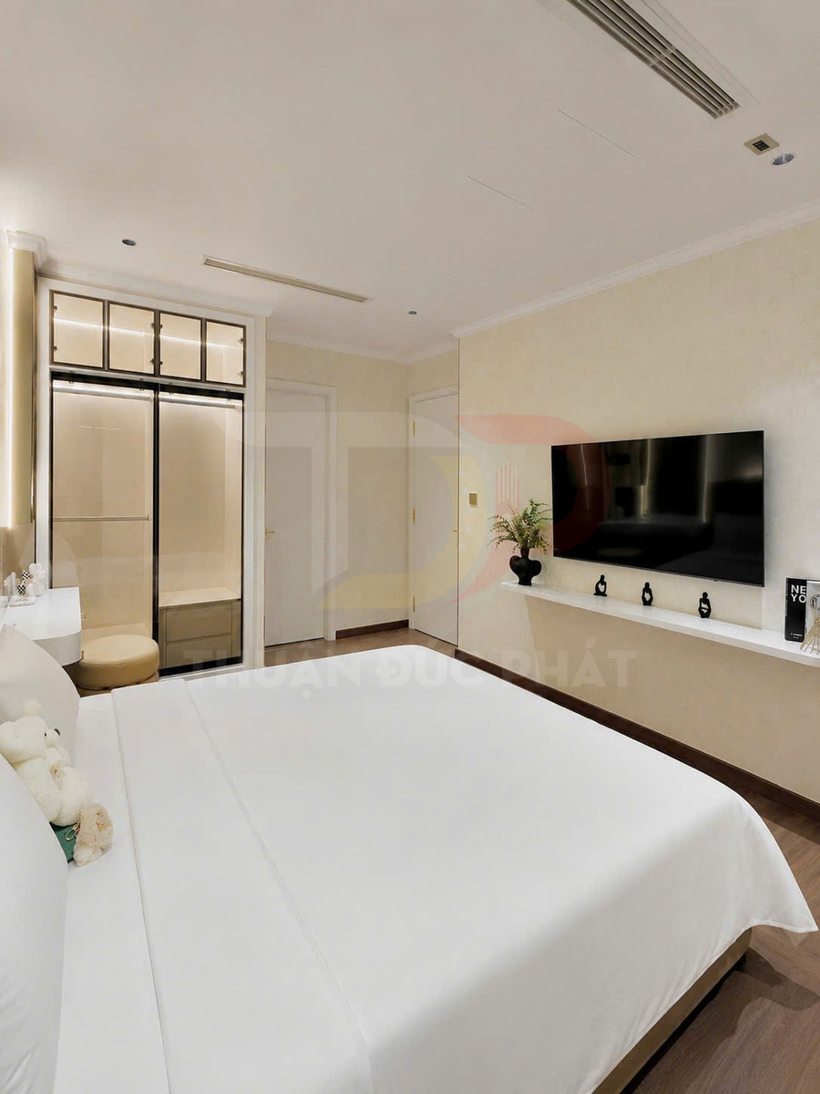 Phòng ngủ hiện đại với giường ngủ ga trắng, tủ quần áo kính trượt và tivi màn hình phẳng treo tường