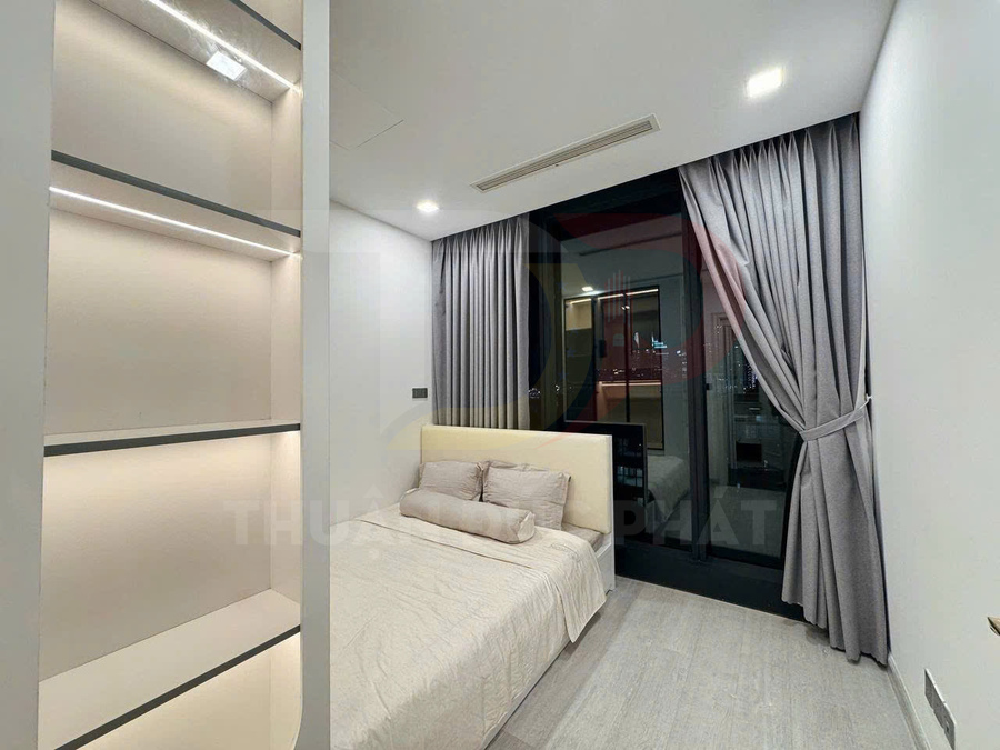 Phòng ngủ hiện đại với giường đôi bọc nệm màu kem, kệ âm tường và rèm cửa sổ lớn màu xám