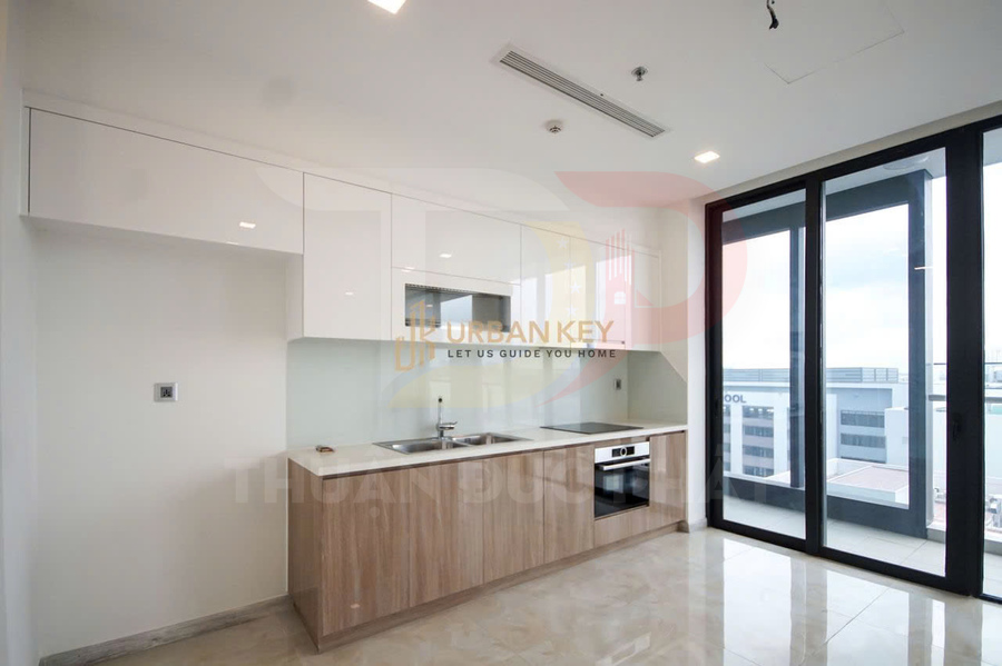 Căn bếp chung cư hiện đại với tủ gỗ, bếp âm, bồn rửa inox và cửa kính lớn nhìn ra ban công
