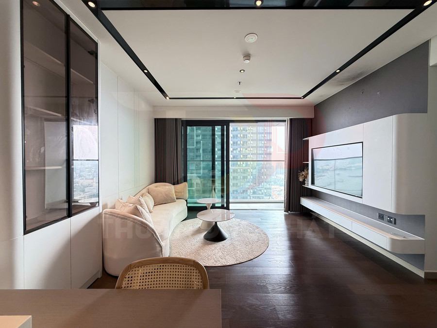 Phòng khách chung cư hiện đại với sofa cong màu kem, bàn trà tròn và kệ tivi treo tường cạnh cửa kính lớn