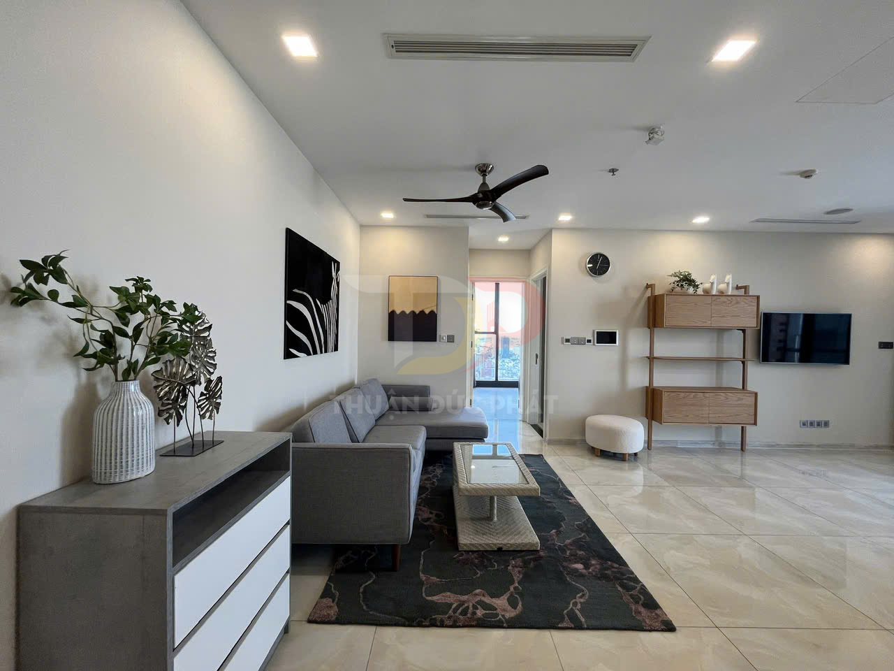 Phòng khách hiện đại với sofa xám, bàn trà, kệ tivi treo tường và tủ gỗ trang trí trên nền gạch sáng