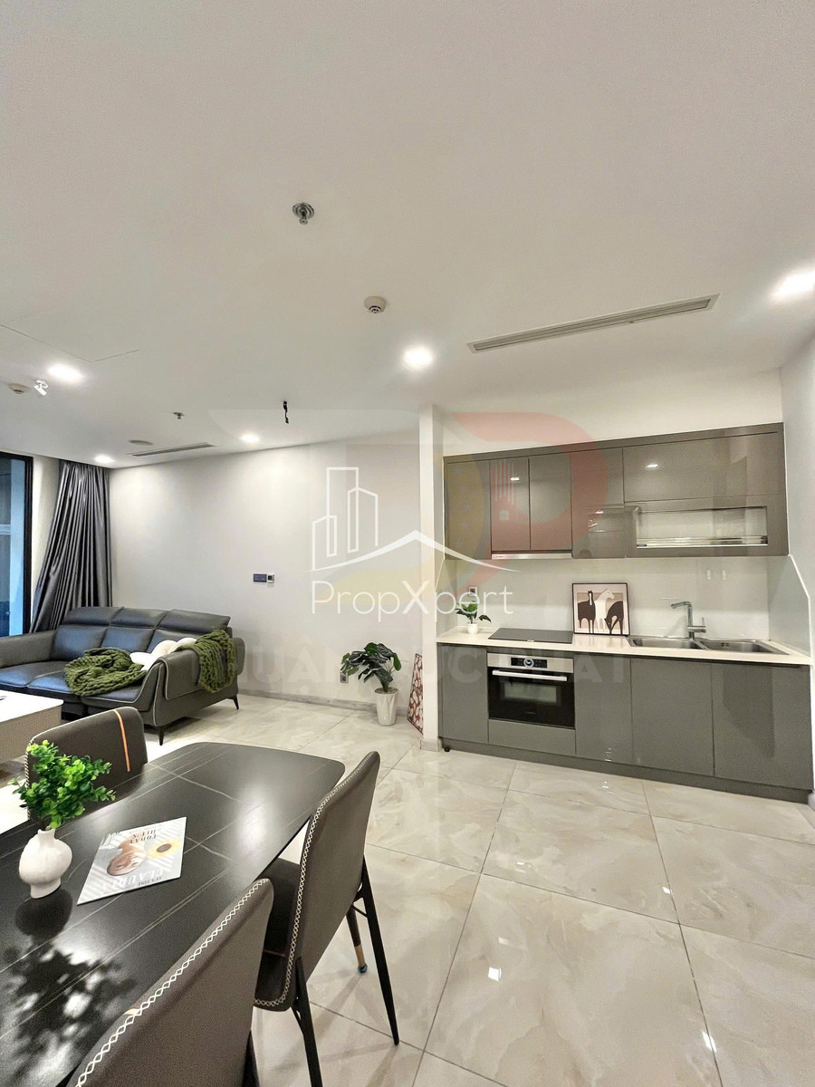 Phòng khách liền bếp hiện đại với sofa da, bàn ăn và tủ bếp âm tường màu xám sáng