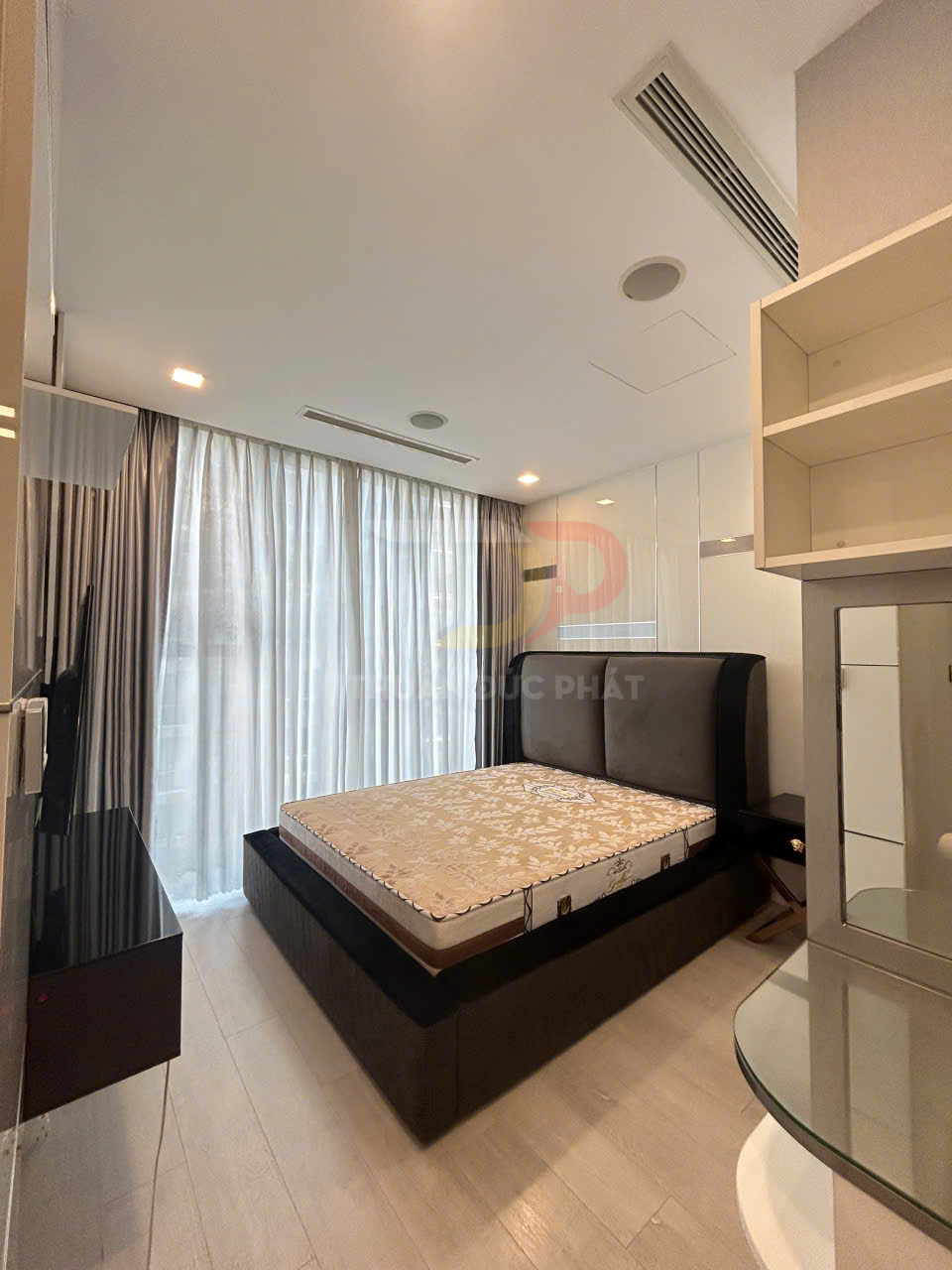 Phòng ngủ nhỏ hiện đại với giường nệm lớn, rèm cửa sổ sáng màu và nội thất gỗ tối giản
