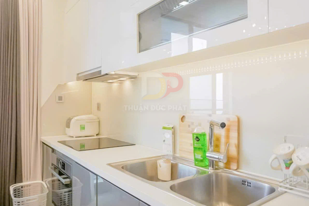 Bếp nhỏ hiện đại với bếp từ, nồi cơm điện, bồn rửa đôi inox và chai nước rửa chén màu xanh