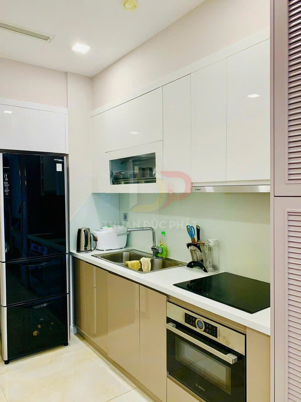 Tủ bếp hiện đại với bếp từ Bosch, lò nướng Bosch, tủ lạnh Hitachi và chậu rửa inox trong căn hộ nhỏ