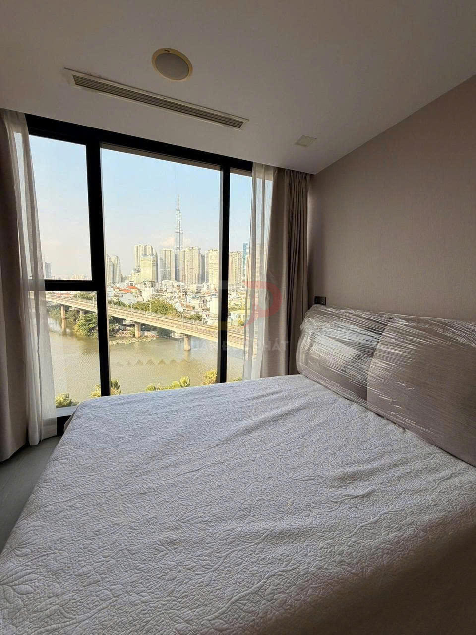 Phòng ngủ căn hộ với giường đôi cạnh cửa sổ lớn view sông và khu đô thị cao tầng