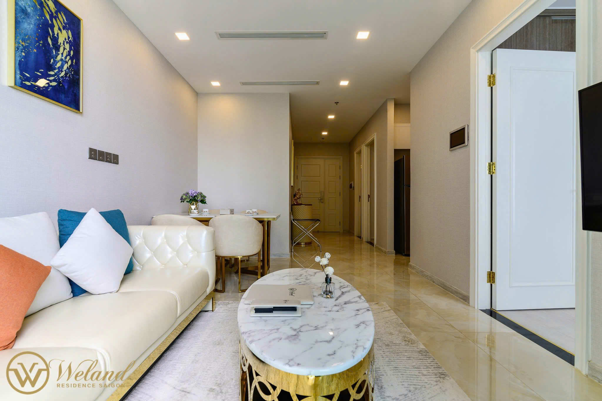 Phòng khách căn hộ cao cấp với sofa da trắng, bàn trà mặt đá và nội thất sang trọng tông vàng kem