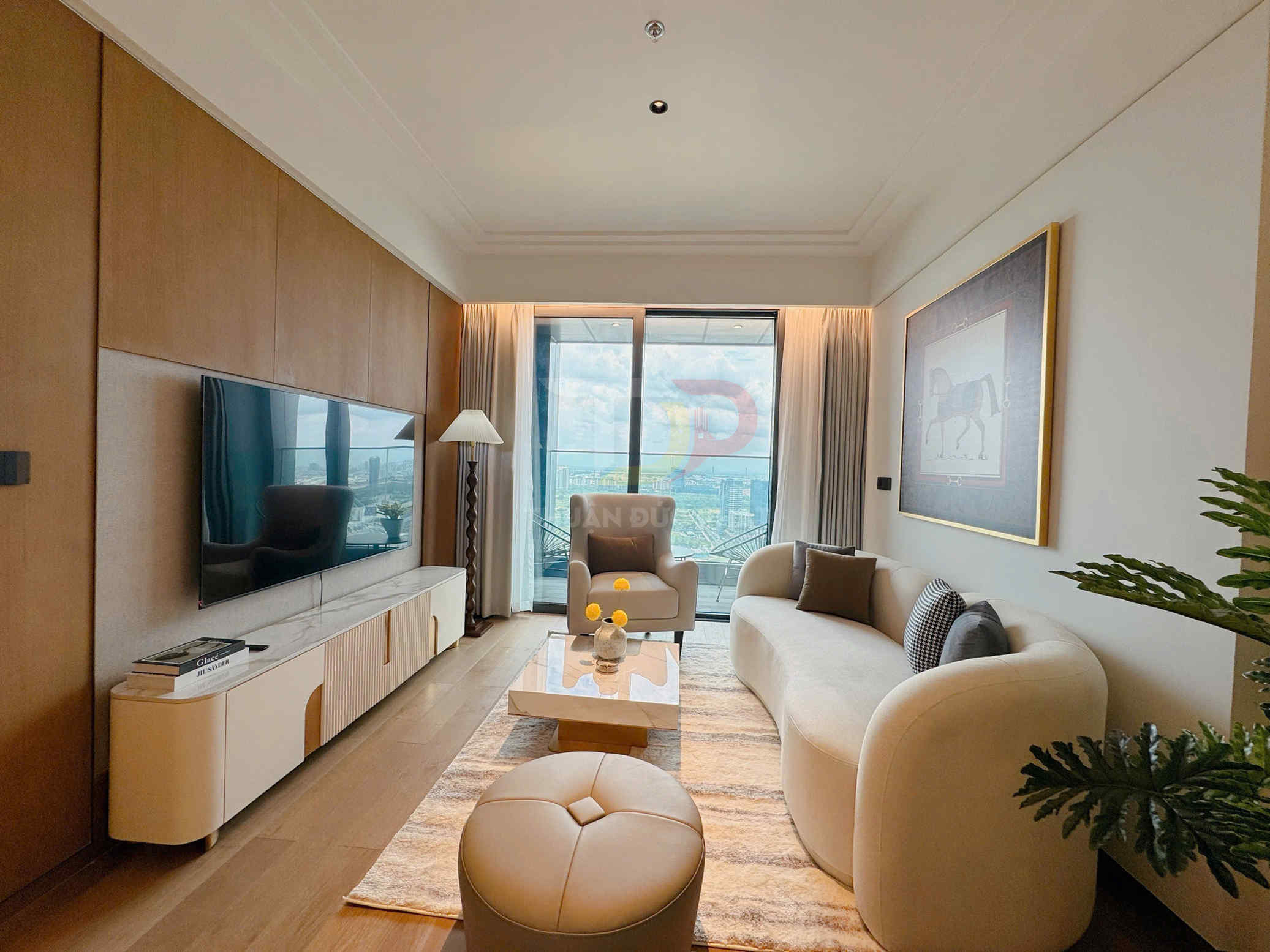 Phòng khách chung cư cao cấp với sofa cong màu kem, bàn trà hiện đại và tivi treo tường cạnh cửa kính lớn