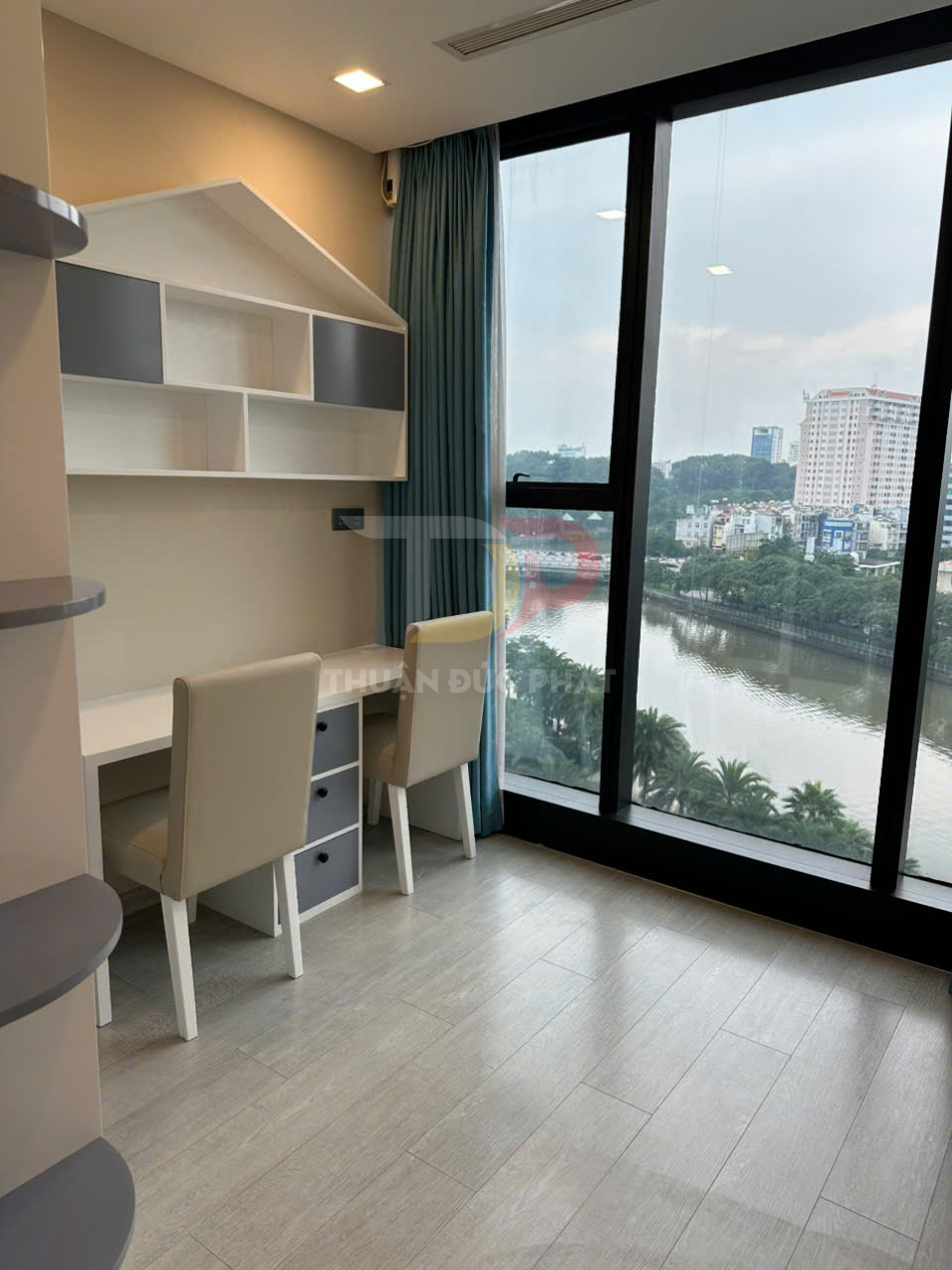 Bàn học đôi màu trắng với ghế bọc da và kệ treo tường cạnh cửa sổ kính lớn view sông