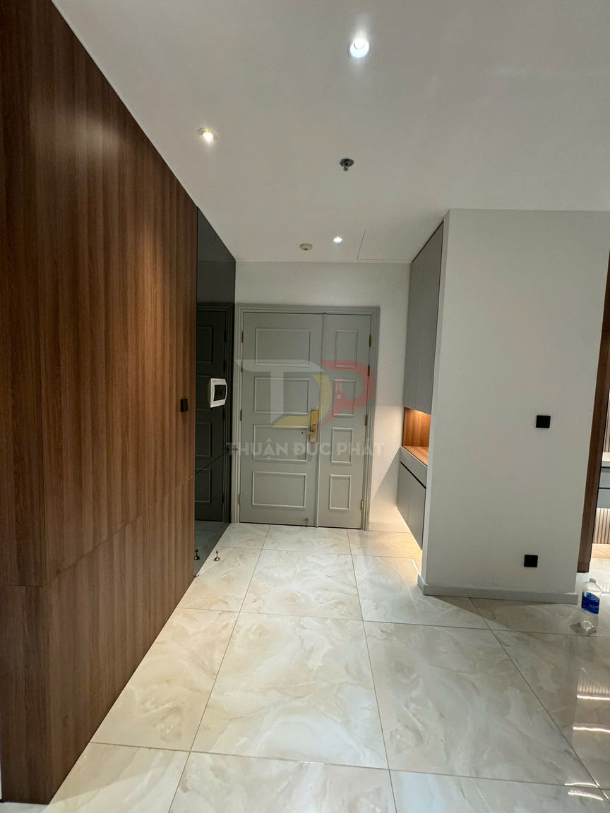 Sàn gạch bóng vân đá màu kem trong hành lang căn hộ hiện đại với tủ gỗ và cửa màu xám