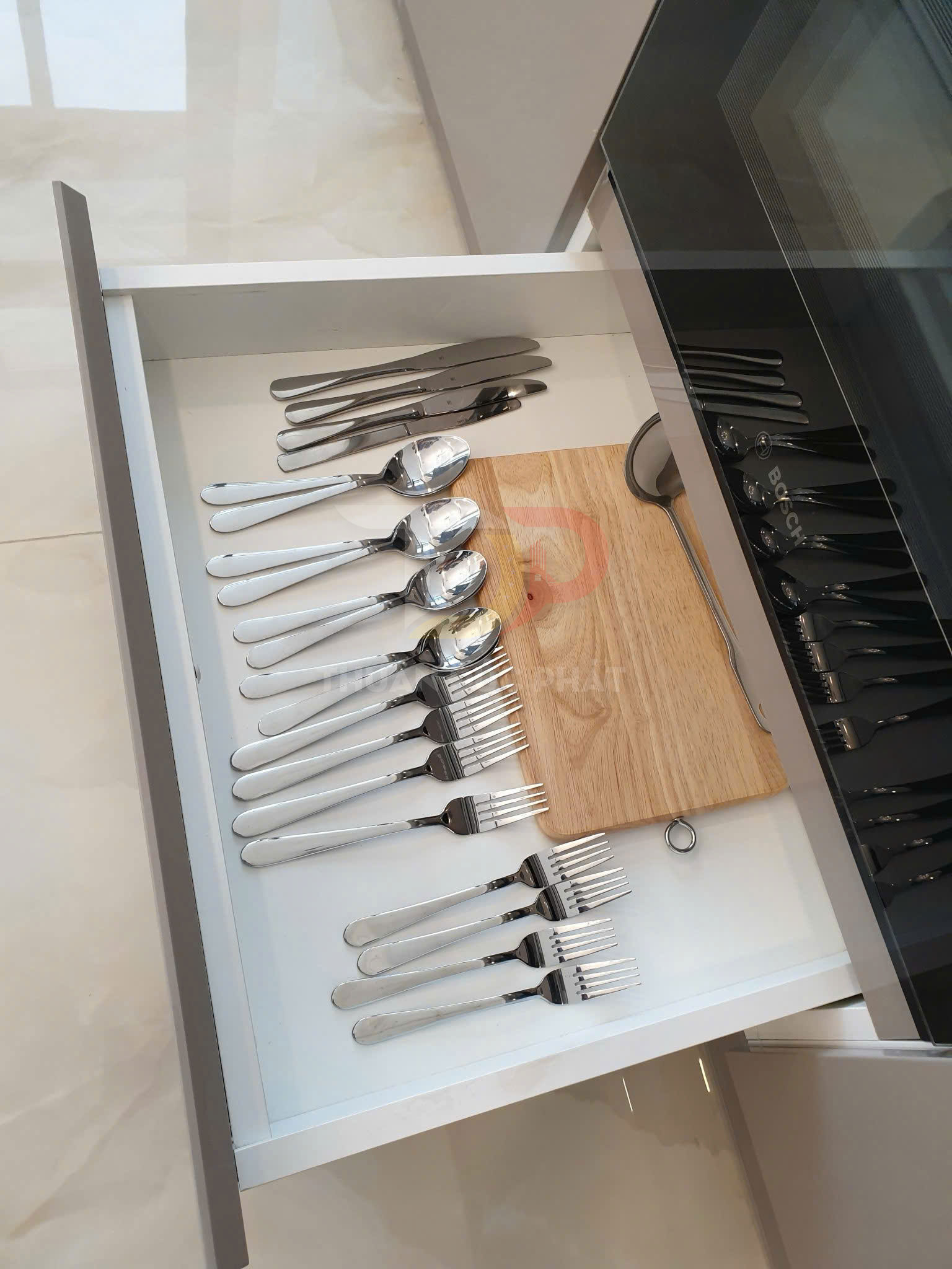 Ngăn kéo bếp gọn gàng với bộ dao thìa nĩa inox và thớt gỗ nhỏ