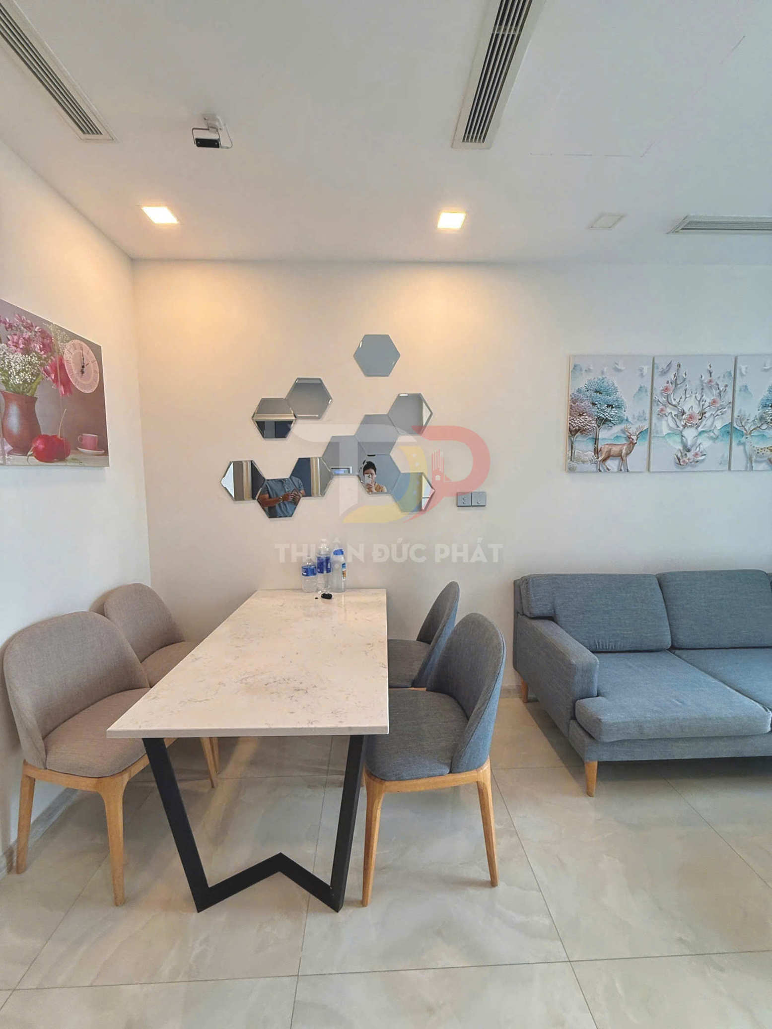 Bàn ăn mặt đá chân sắt chữ V kèm ghế nệm và sofa vải xám trong phòng khách hiện đại