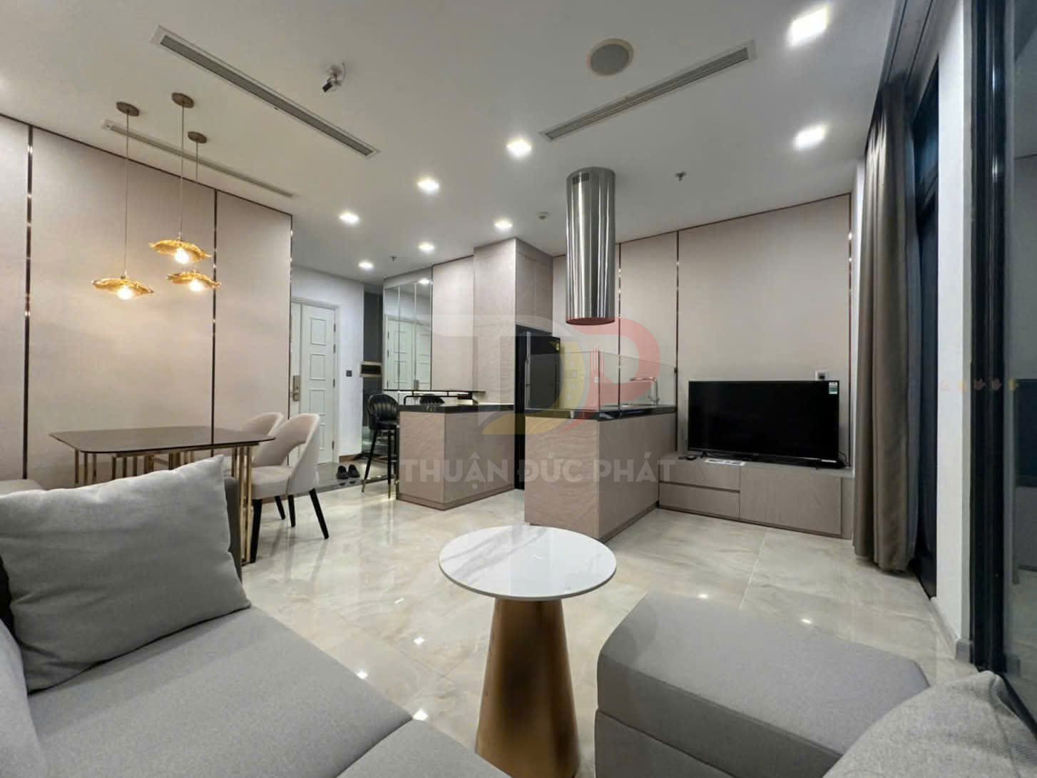 Phòng khách căn hộ hiện đại với sofa xám, bàn trà tròn, bàn ăn và tivi màn hình phẳng trên kệ gỗ