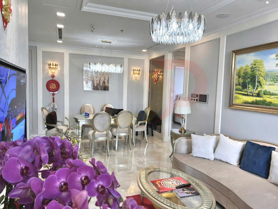 Phòng khách căn hộ cao cấp với sofa chữ L, bàn trà kính, bàn ăn sáu ghế và đèn chùm pha lê sang trọng