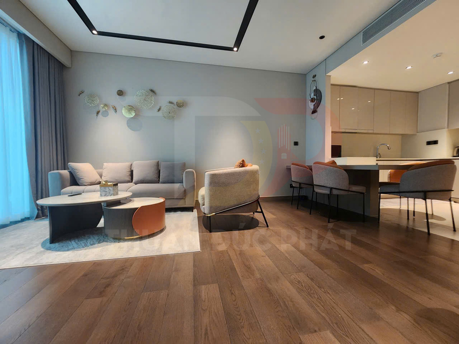Phòng khách hiện đại với sofa xám, bàn trà tròn và sàn gỗ liền kề khu bếp tích hợp bàn ăn