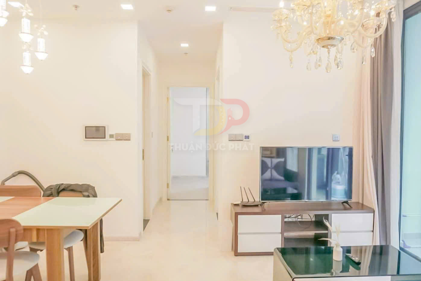 Phòng khách chung cư hiện đại với tivi màn hình phẳng trên kệ gỗ và bàn ăn gỗ cạnh cửa kính lớn