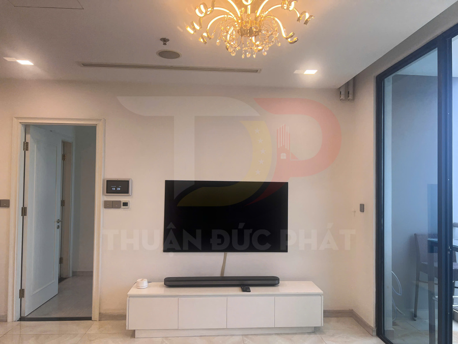 Tivi màn hình phẳng treo tường với loa soundbar trên kệ trắng trong phòng khách hiện đại