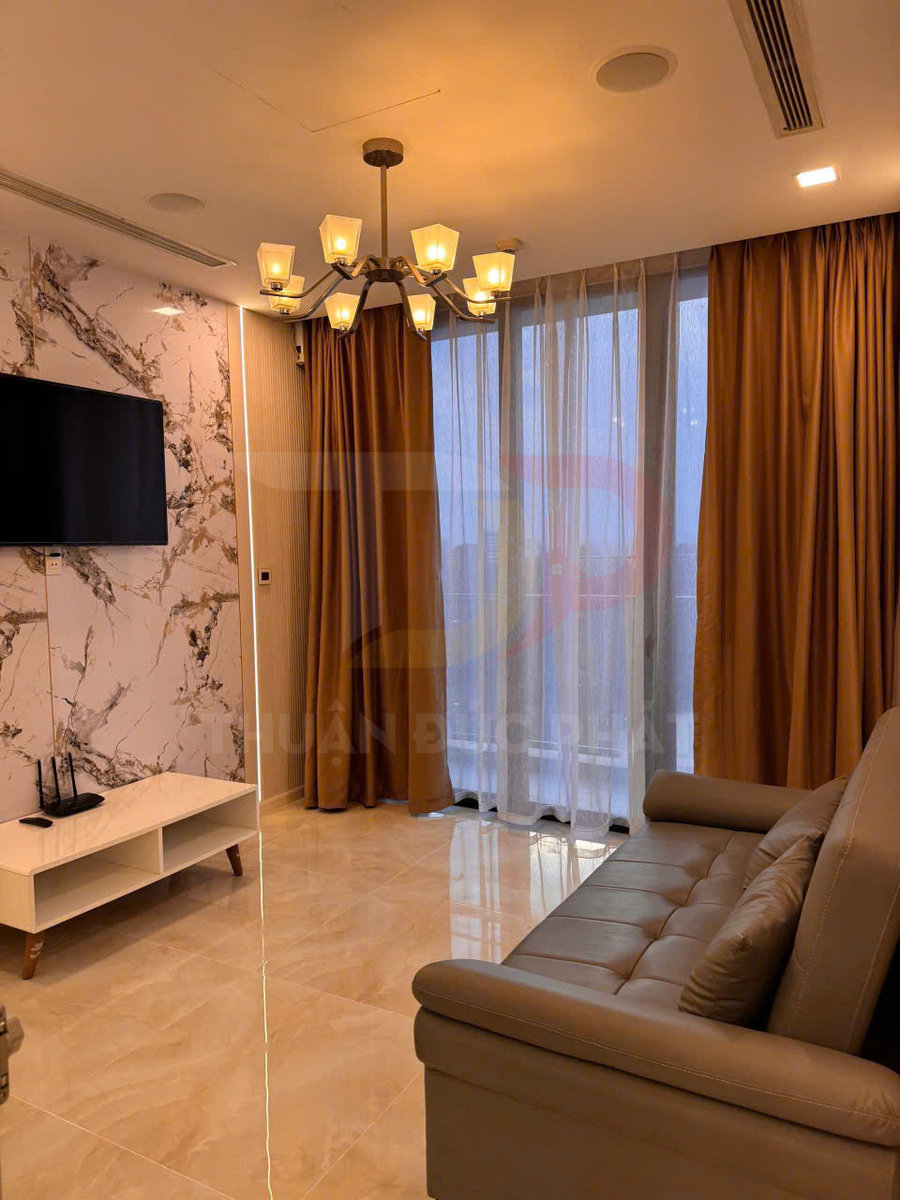 Phòng khách chung cư hiện đại với sofa da, đèn chùm trần, tivi treo tường và rèm cửa lớn màu nâu