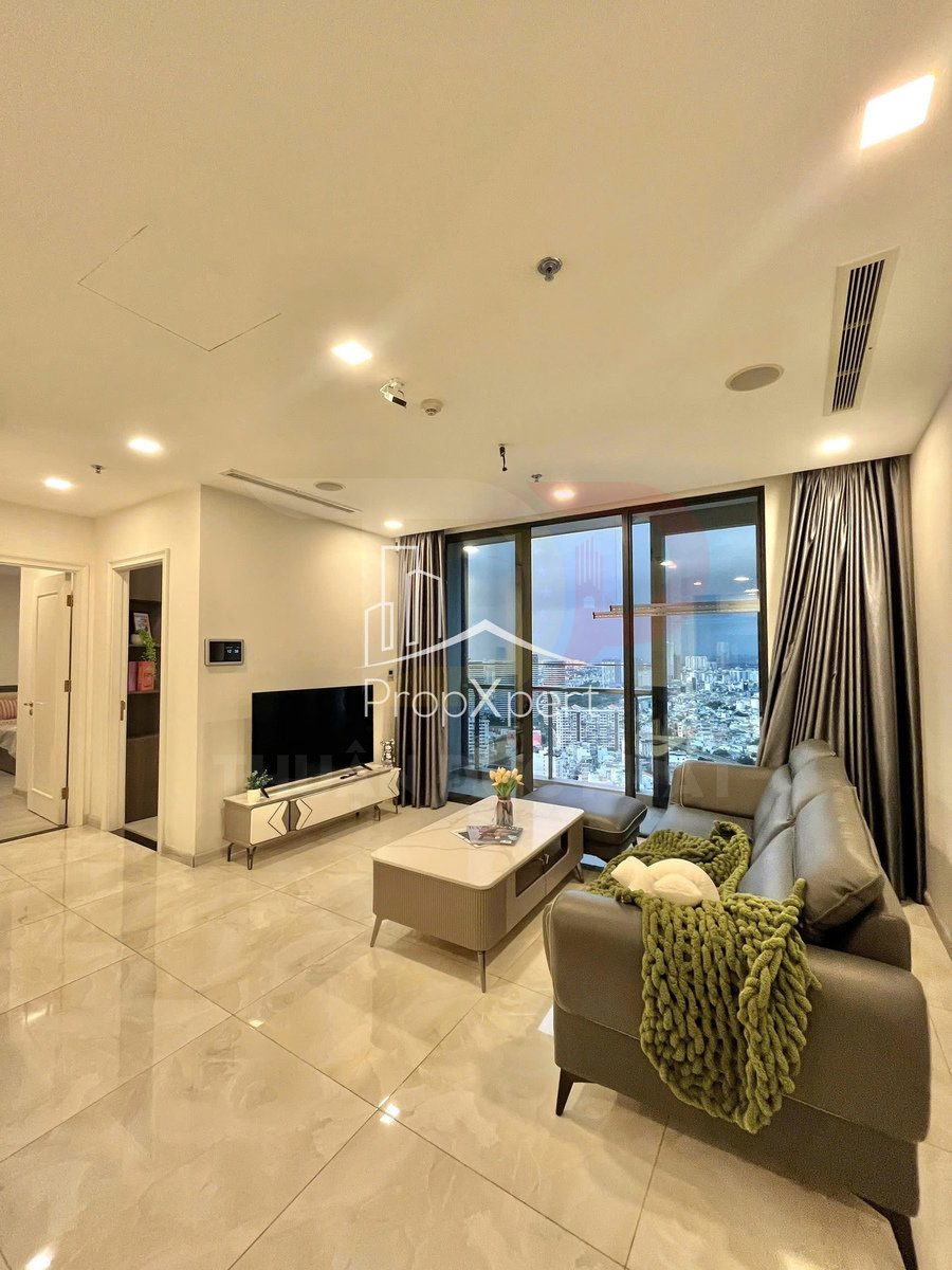 Phòng khách căn hộ hiện đại với sofa da xám, bàn trà, tivi treo tường và cửa kính lớn nhìn ra thành phố