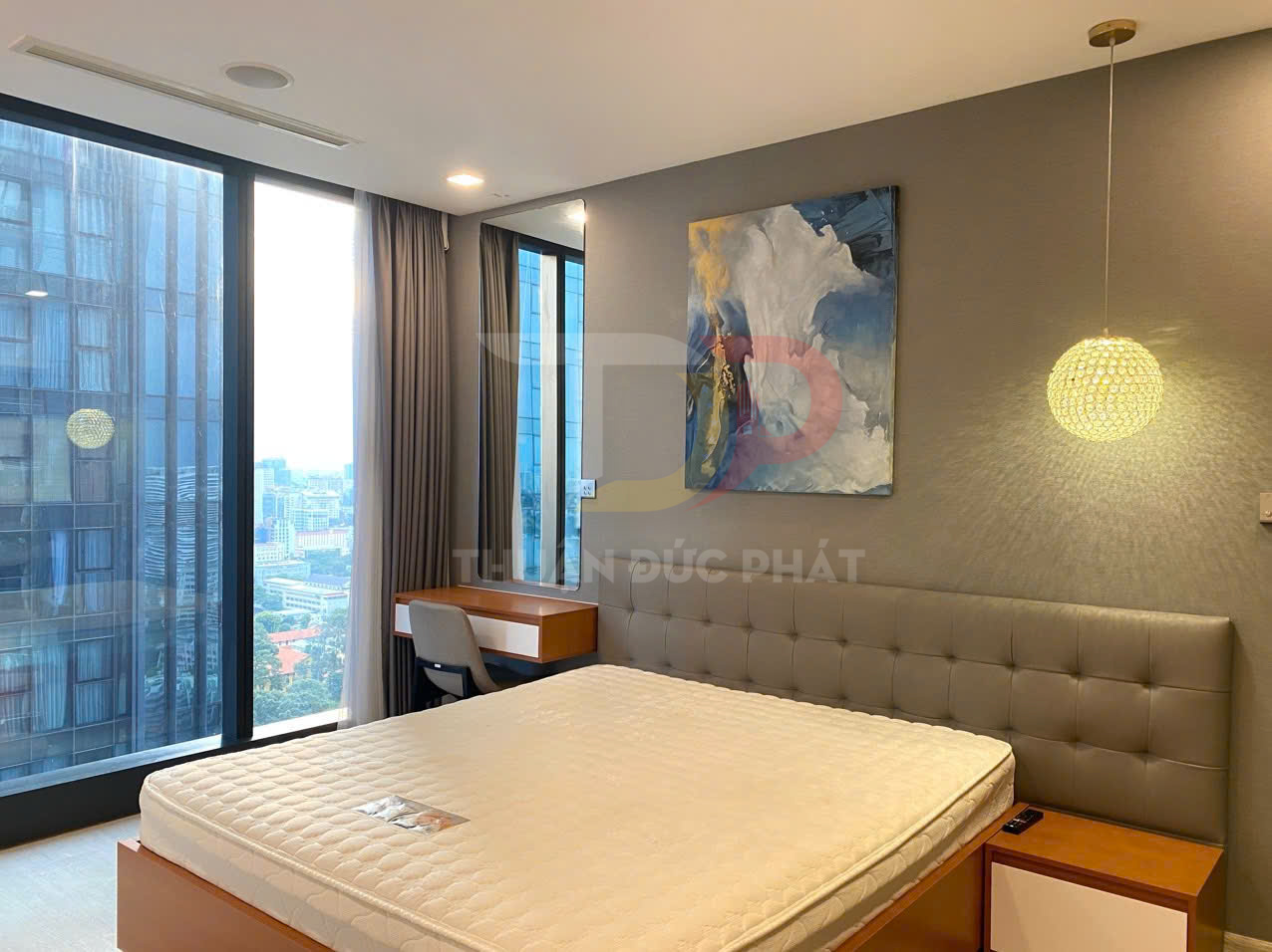 Phòng ngủ hiện đại với giường nệm lớn cạnh cửa sổ kính toàn cảnh và bàn làm việc gỗ nhỏ